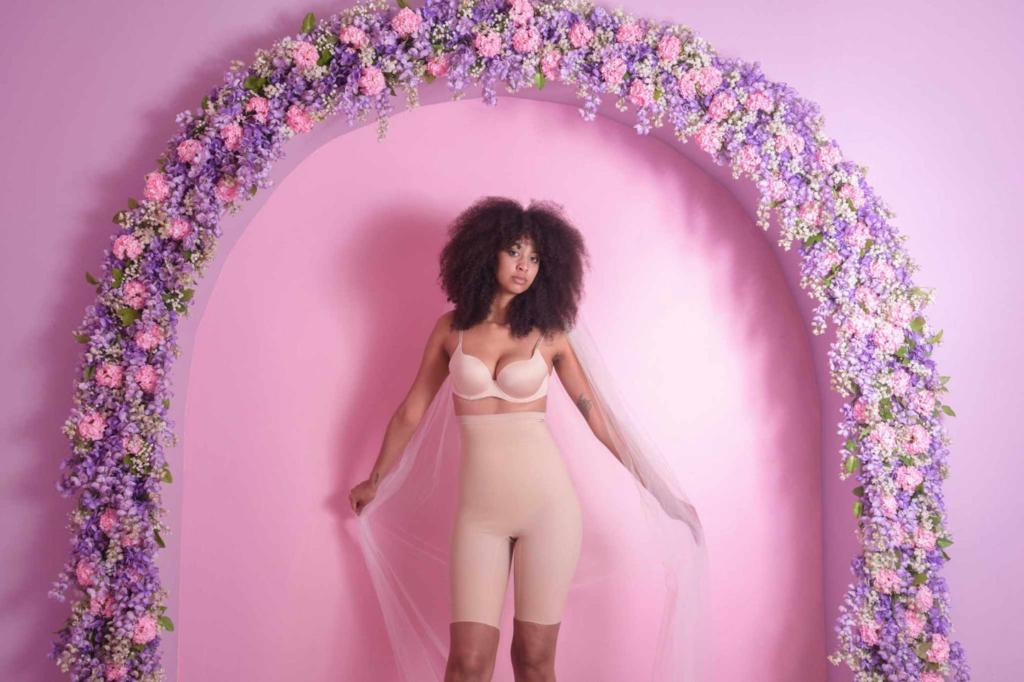 woman wearing shelby seamless high rise shorts under floral arch.