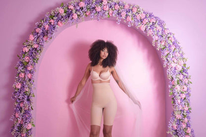 Woman wearing SHELBY SEAMLESS HIGH RISE SHORTS under floral arch.